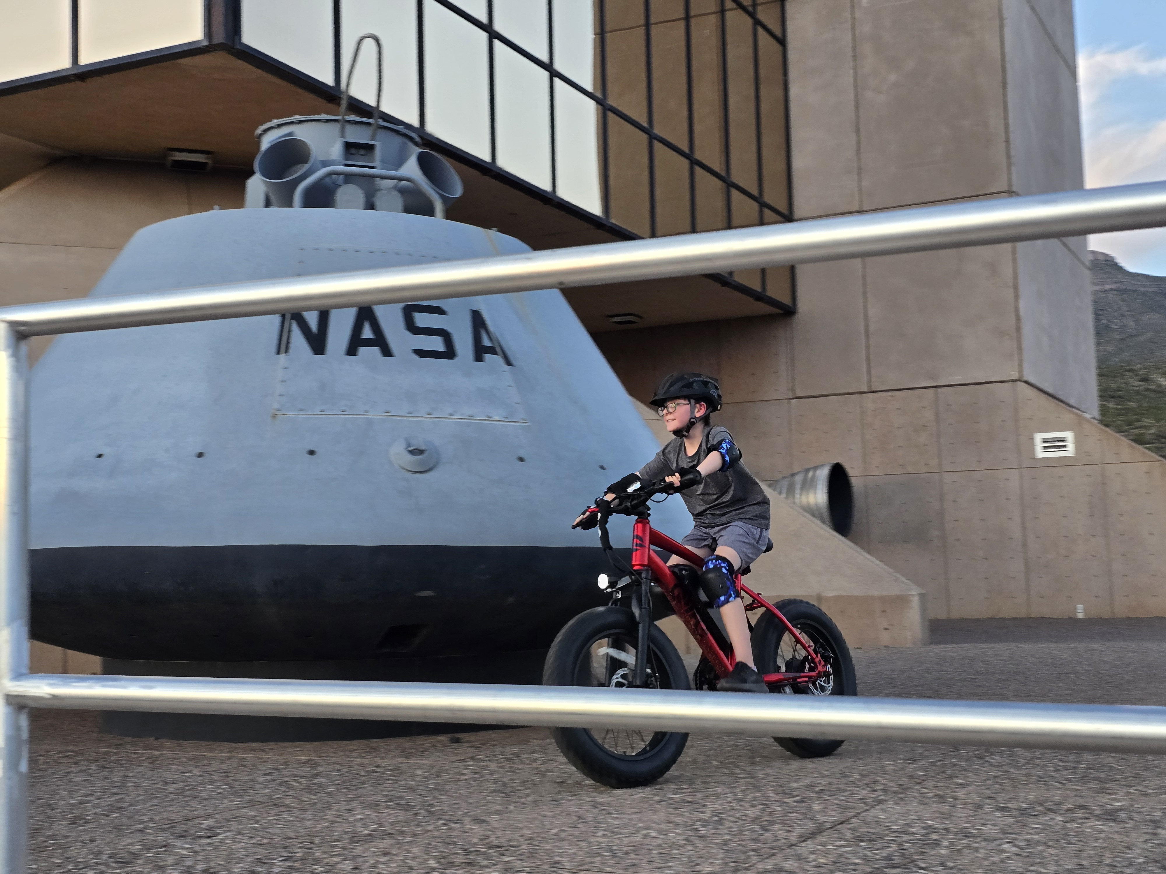 The image shows a boy riding a electric bicycle through the Space History Museum